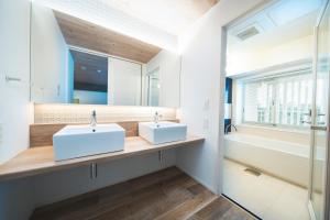 two white sinks in a bathroom with a window at BEB5 Okinawa Seragaki by Hoshino Resorts in Onna