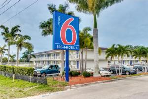 una señal para un hotel con coches estacionados en un estacionamiento en Motel 6-Venice, FL, en Venice