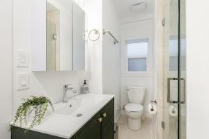 a white bathroom with a sink and a toilet at Vancouver Central Green Studio in Vancouver +6 photos