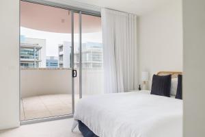 Un dormitorio con una cama blanca y una ventana grande. en Portside on Honeysuckle, en Newcastle