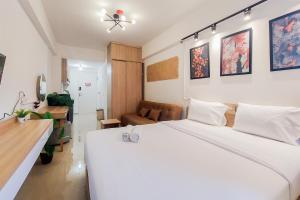 タンゲランにあるGood Choice Studio Apartment Aeropolis Residence By Travelioの大きな白いベッドとソファのある寝室