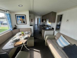 - soggiorno con divano e tavolo in roulotte di Family Beach Getaway, Pools, Mountains and more a Prestatyn