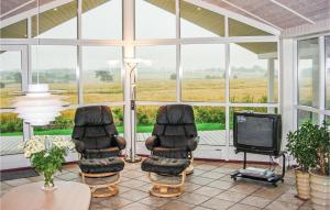 a screened in porch with two chairs and a tv at Holiday Home Houmøllevej in Karby