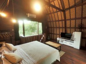 a bedroom with a bed and a television in a room at 2 storey wooden house in the heart of Uluwatu in Uluwatu