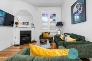 a living room with two green couches and a fireplace at 'Urban Chic on Grey' - 3 Bedroom Retreat in Wickham in Wickham