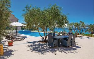 un patio con tavolo e sedie accanto alla piscina di Cozy Apartment In Povljana With Kitchen a Povljana (Pogliana) Altre 30 foto