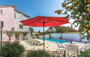 a red umbrella sitting in front of a pool at 1 Bedroom Amazing Apartment In Banjole in Banjole