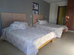 two beds sitting next to each other in a bedroom at Hotel Bonanza in Cuernavaca +1 photo