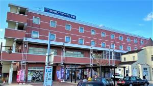 a large red building with cars parked in front of it at Ryugasaki Plaza Hotel Shinkan in Ryūgasaki