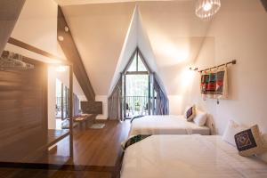 a attic bedroom with two beds and a window at Casa Vanilla Mang Den in Kon Von Kla