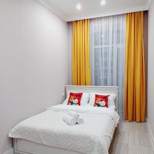 een slaapkamer met een wit bed met rode kussens bij Отличная квартира ЖК Алпамыс in Astana