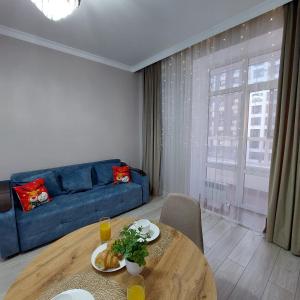 een woonkamer met een blauwe bank en een tafel bij Отличная квартира ЖК Алпамыс in Astana