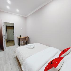 een witte slaapkamer met een groot bed met rode kussens bij Отличная квартира ЖК Алпамыс in Astana
