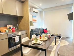 メルボルンにあるMT2506 - 1 BR huts nestled in the Docklands with Gym & Poolのテーブルと椅子のあるキッチンとリビングルーム