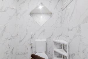 タンゲランにあるCozy with Modern Design Studio Parkland Avenue Apartment By Travelioの白い大理石の壁のバスルーム(トイレ付) +10枚の写真
