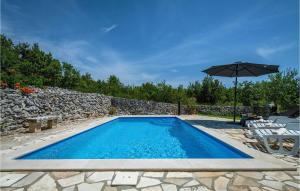 a swimming pool with an umbrella next to a stone wall at Holiday Home Burjaki Cr in Trgetari