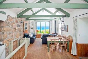 a living room with a table and a stone wall at Girl Annie, Cornish Cottage With Superb Sea Views & Garden, By Beach in Sennen