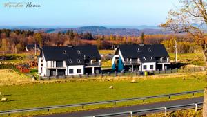 a group of houses in a field with sheep in the grass at Wonder Home - Domek Sielsko Czarodziejsko blisko Karpacza, z kominkiem, z widokiem na góry i tarasem in Ściegny