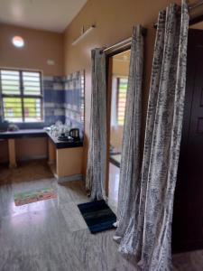 baño con una puerta con cortinas en una habitación en JOLFORING Home Stay, en Santiniketan