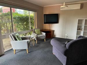 a living room with chairs and a flat screen tv at Ulladulla Harbour Motel in Ulladulla