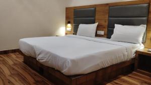a bedroom with a large white bed with a wooden headboard at Hotel Hoxton in Mumbai