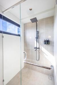 een douche met een glazen deur in een badkamer bij Santos Suites in Badung +42 foto's