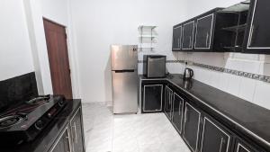 a kitchen with black cabinets and a stainless steel refrigerator at Hirikatiya Edge in Dickwella