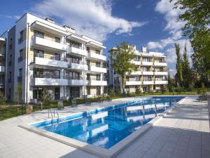 an apartment building with a swimming pool in front of a building at Equilibrium Apartments in Ustronie Morskie