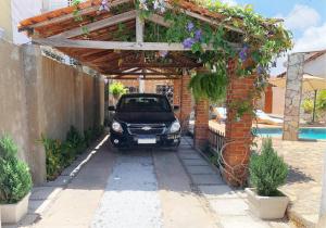 Ein Auto parkt unter einer Pergola neben einem Pool in der Unterkunft Sobrado piscina a 200m orla, perfeito para festa in Paulista