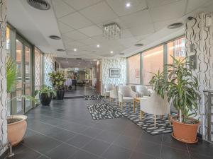 a lobby with a waiting room with chairs and plants at Holiday Beach Budapest Wellness Hotel with Sauna Park in Budapest +37 photos