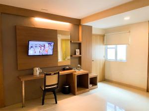 a room with a desk and a television on the wall at Winstar Hotel in Pekanbaru