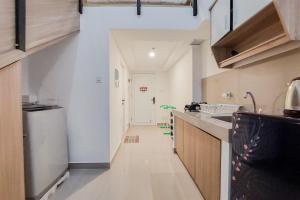a kitchen with white walls and a long hallway at Spacious and Elegant Studio Loft Kingland Avenue Apartment By Travelio in Tangerang