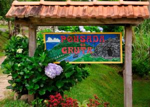 un cartel para un parque en un jardín con flores en Pousada da Gruta, en Visconde De Maua