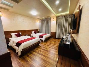 a hotel room with two beds and a television at Hotel Nova Nook Pvt Ltd in Kathmandu
