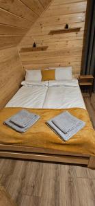 a bed in a wooden room with two towels on it at Domek Pod Skarpą in Wieprzec +33 photos