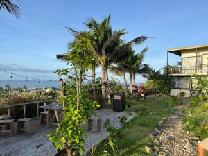 a wooden deck with palm trees and a house at Peaceful Hill Homestay in Ke Ga