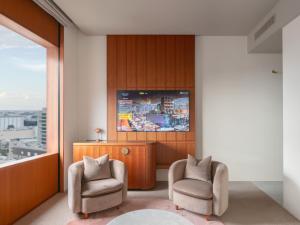 a living room with two chairs and a tv at The Mark Grand Hotel in Saitama