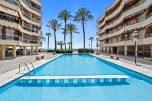 a swimming pool in front of a building with palm trees at Appartement Cambrils front de mer in Cambrils