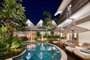 einen Innenpool in einem Hotel mit Tischen und Stühlen in der Unterkunft Aeera Villa Canggu by Ini Vie Hospitality in Canggu