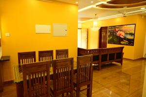 a dining room with chairs and a yellow wall at Days inHome in Paravūr