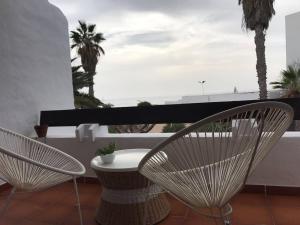 dwa krzesła i stół na balkonie z palmami w obiekcie La playita, primera linea de mar w Puerto del Carmen
