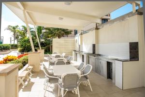 un patio al aire libre con mesas y sillas blancas en Paradise Centre Apartments, en Gold Coast