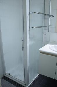 a white bathroom with a shower and a sink at Appart avec terrasse proche mer in De Panne