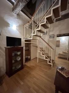 a living room with a staircase and a television at DorminColle - Appartamento in stile toscano in Colle di Val d'Elsa