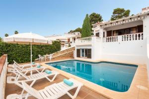a villa with a swimming pool with chairs and an umbrella at Villa Catalina by Escape Home in Alaior +7 photos
