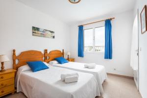 two beds in a bedroom with blue curtains at Villa Catalina in Alaior