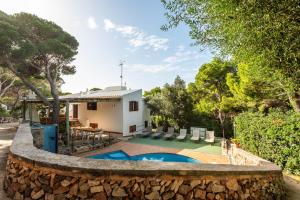 a house with a swimming pool and a stone wall at Villa Can Biel by Escape Home in Cala Morell