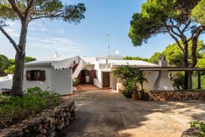 a white house with a stone wall and trees at Villa Can Biel by Escape Home in Cala Morell