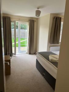 une chambre avec un lit et une porte coulissante en verre dans l'établissement YBC Court, Aldershot, à Aldershot