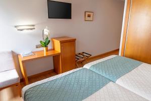 康达Hotel Faranda Marsol Candas, Ascend Hotel Collection的一间卧室，配有一张床和一张带电视的书桌